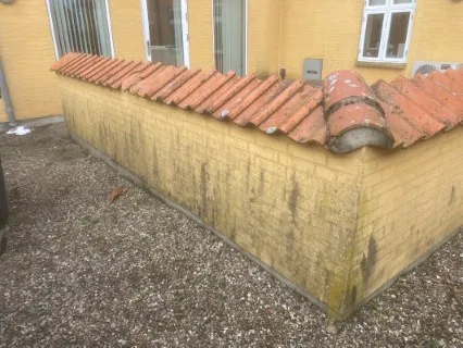 Gul mur med tegltag før rensning